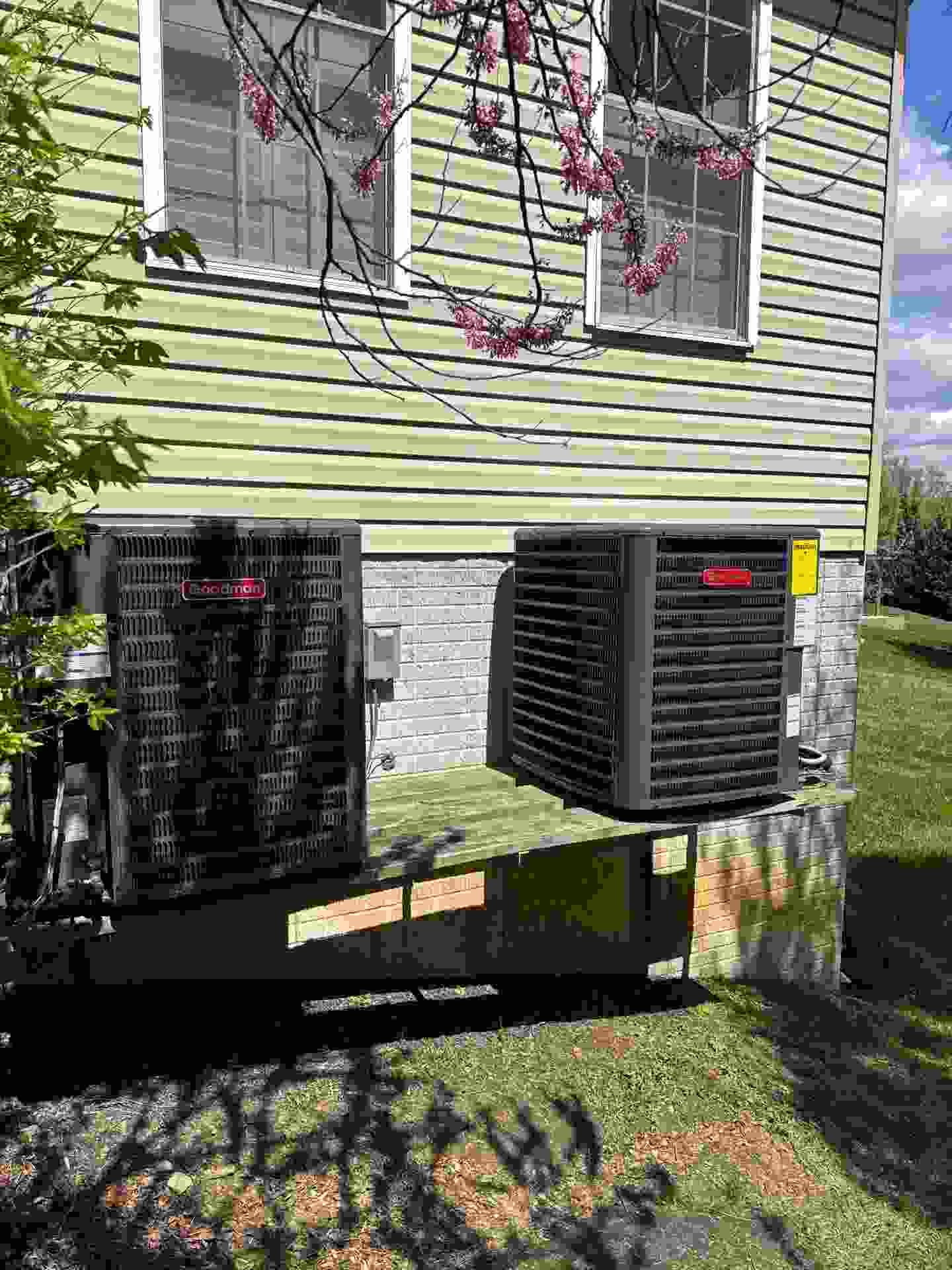 Technician cleaning a spring HVAC unit outside a Baltimore home